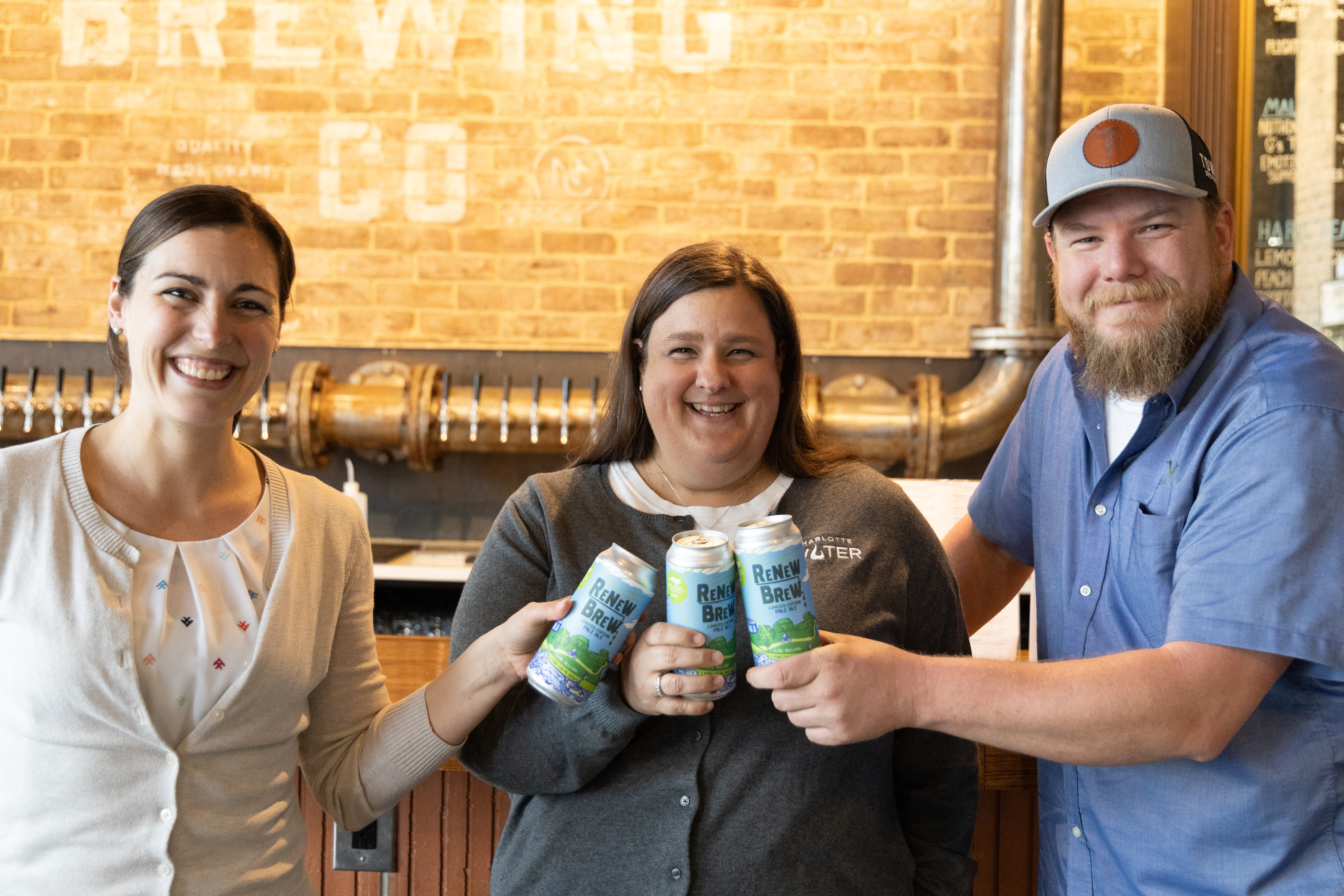 Nicole Pennington (Xylem), Jennifer Frost (Charlotte Water), and Brandon Stirewalt (Town Brewing Company) posing with cans of Renew Brew.