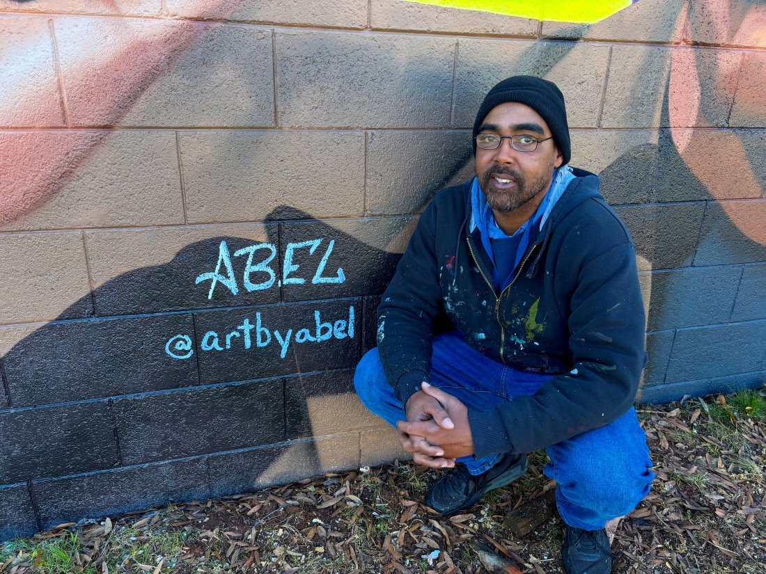Artist Abel Jackson stands next to artist tag