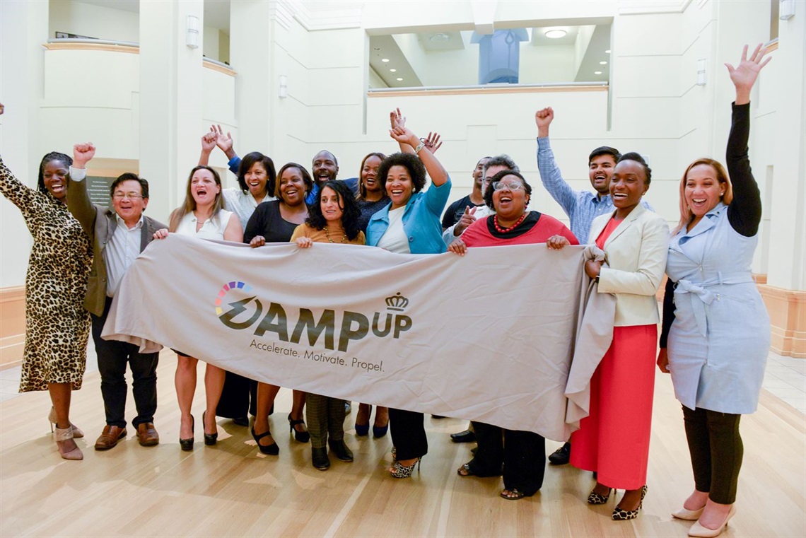 AMP Up Charlotte graduates and city staff celebrating and hold AMP Up banner