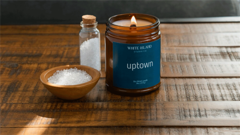 The “Uptown” candle from White Island Studio Co. on a wooden coffee table.