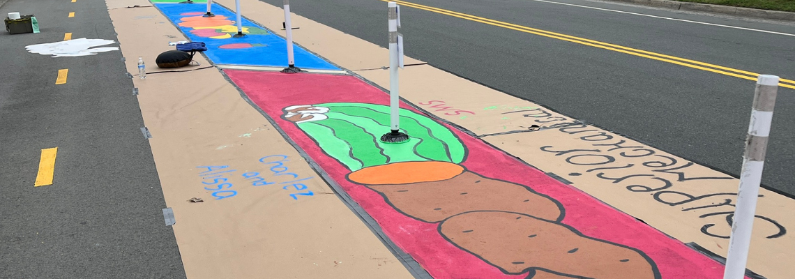 Progress photo of the “Paint the Pavement with Nutrition” mural painted along the bike lane on the 300 block of Davidson Street.