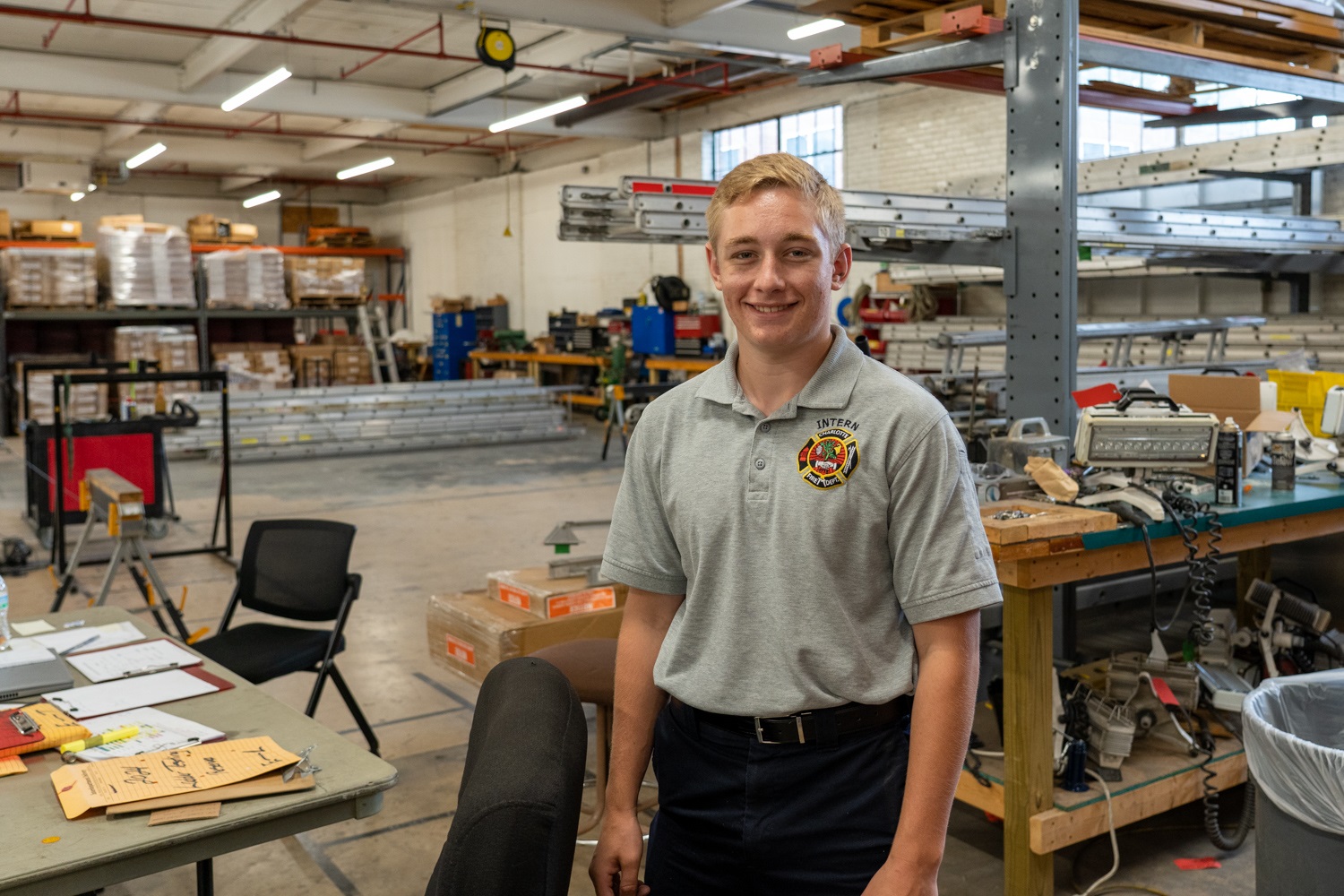 MYEP intern Dylan smiles in a Charlotte Fire polo in front of the firehouse where he interned.