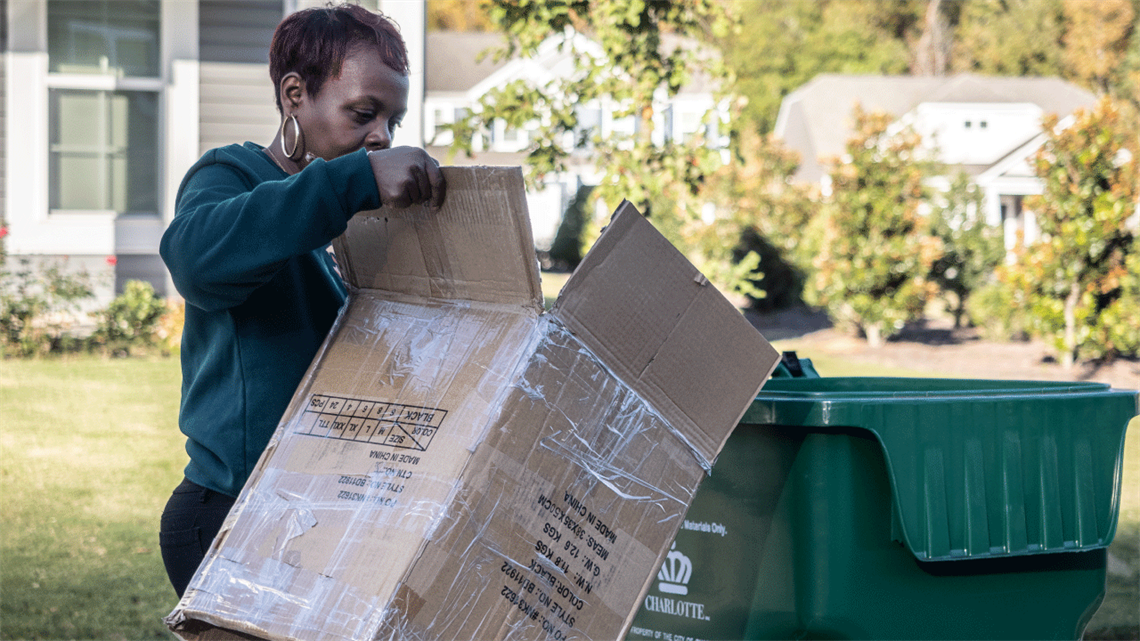 Woman placing cardboard box in recycling bin