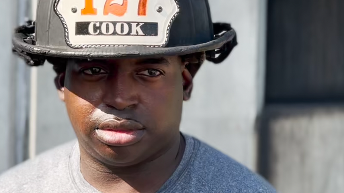 Caption Cook stares ahead, wearing his Recruiting Class 127 helmet that displays his name.