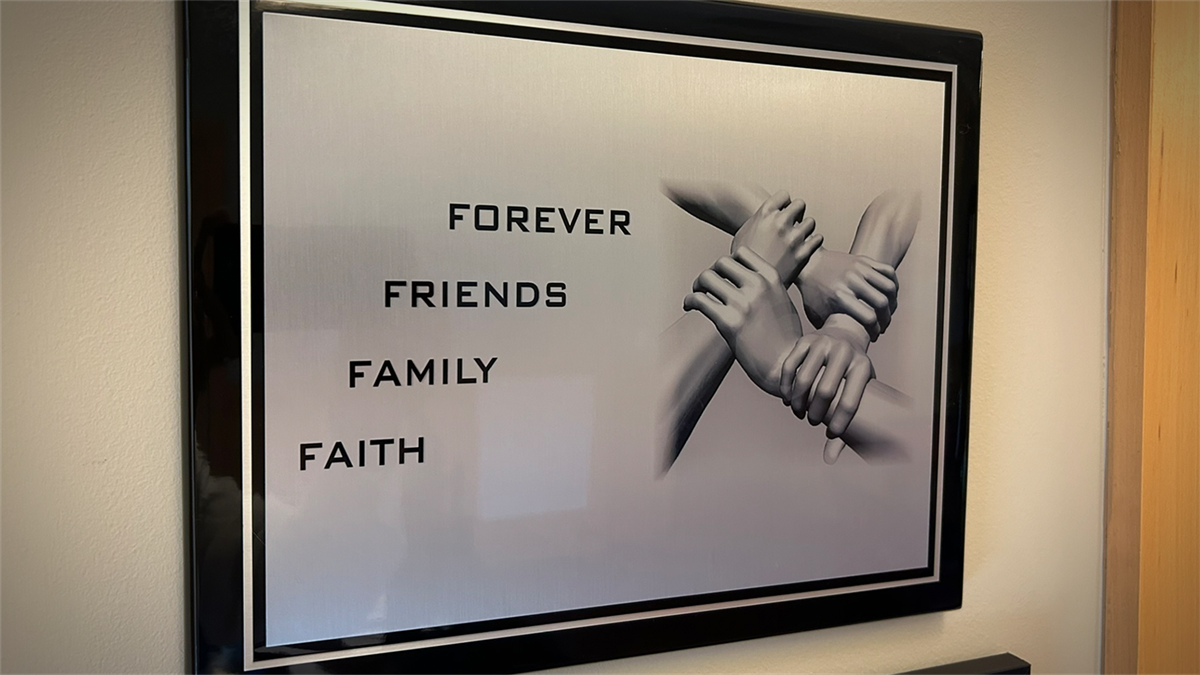 A framed image that displays four hands, each holding the wrist of another arm, with text that reads, 'Forever. Friends. Family. Faith.