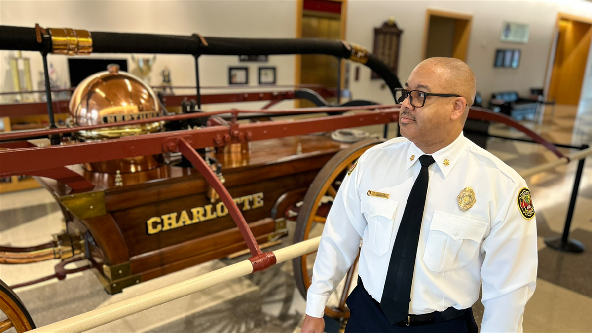 Fire Chief Reggie Johnson standing in front of the Neptune pumper at Charlotte Fire headquarters.