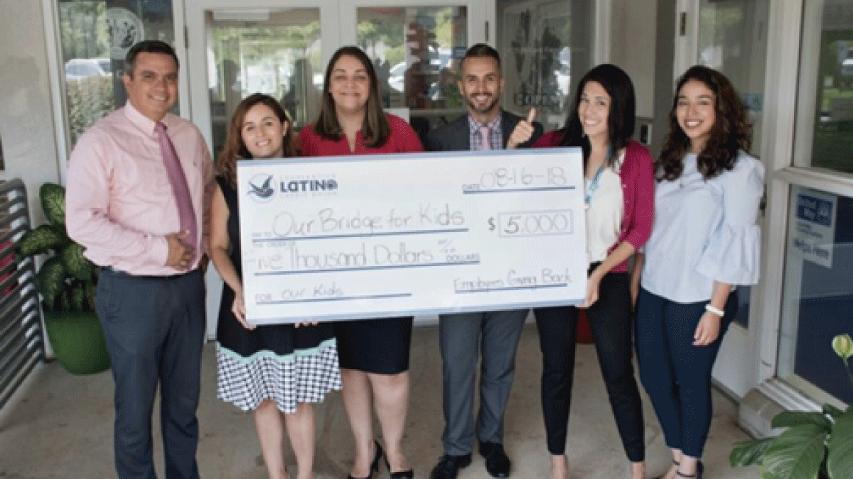 LCCU employees hold large check for money raised for Charlotte-based ourBRIDGE for KIDS through Employees Giving Back program