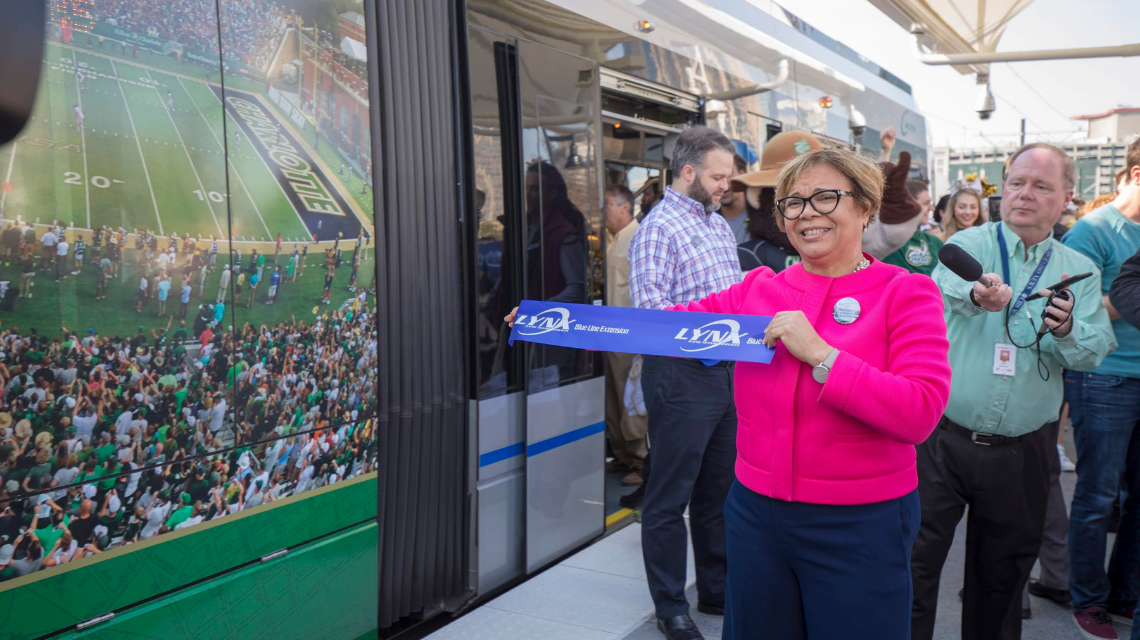 Lyles standing in front of a CATS Lynx train car holding up a towel with the CATS Lynx insignia.