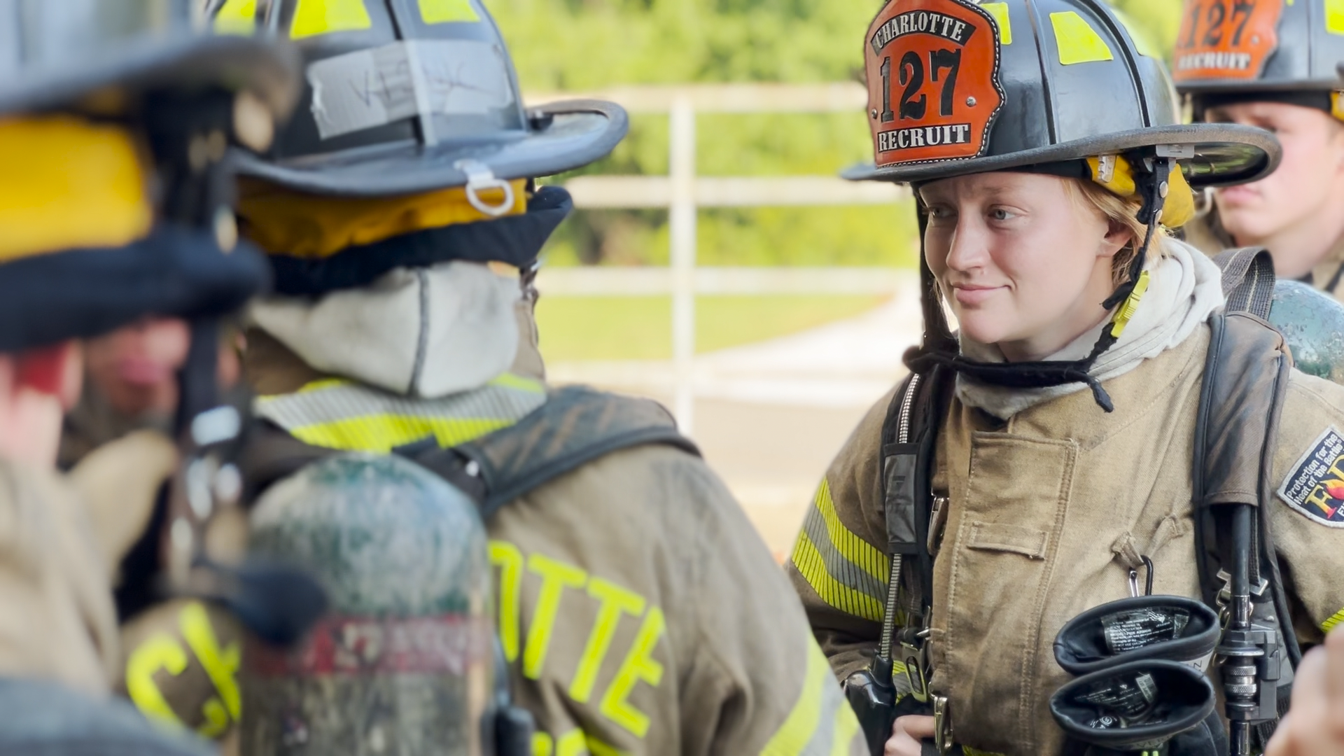Gazerro interacts with fellow Charlotte Fire recruits during training. Everyone is in full gear.