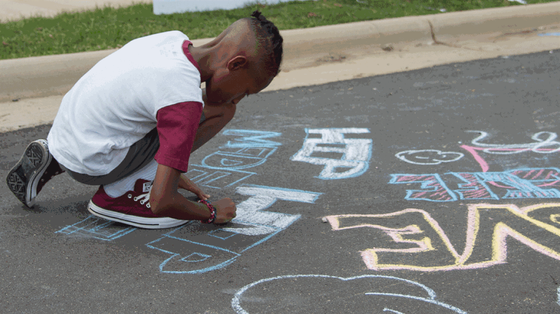 Young resident creating chalk art at Open Streets 704 event