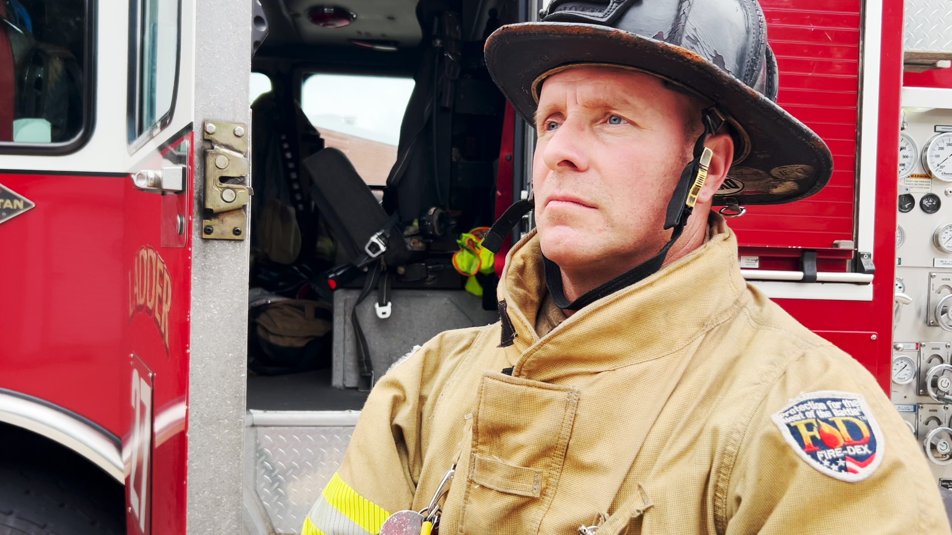 Firefighter Matt Wiatrowski standing outside a fire engine in full gear.