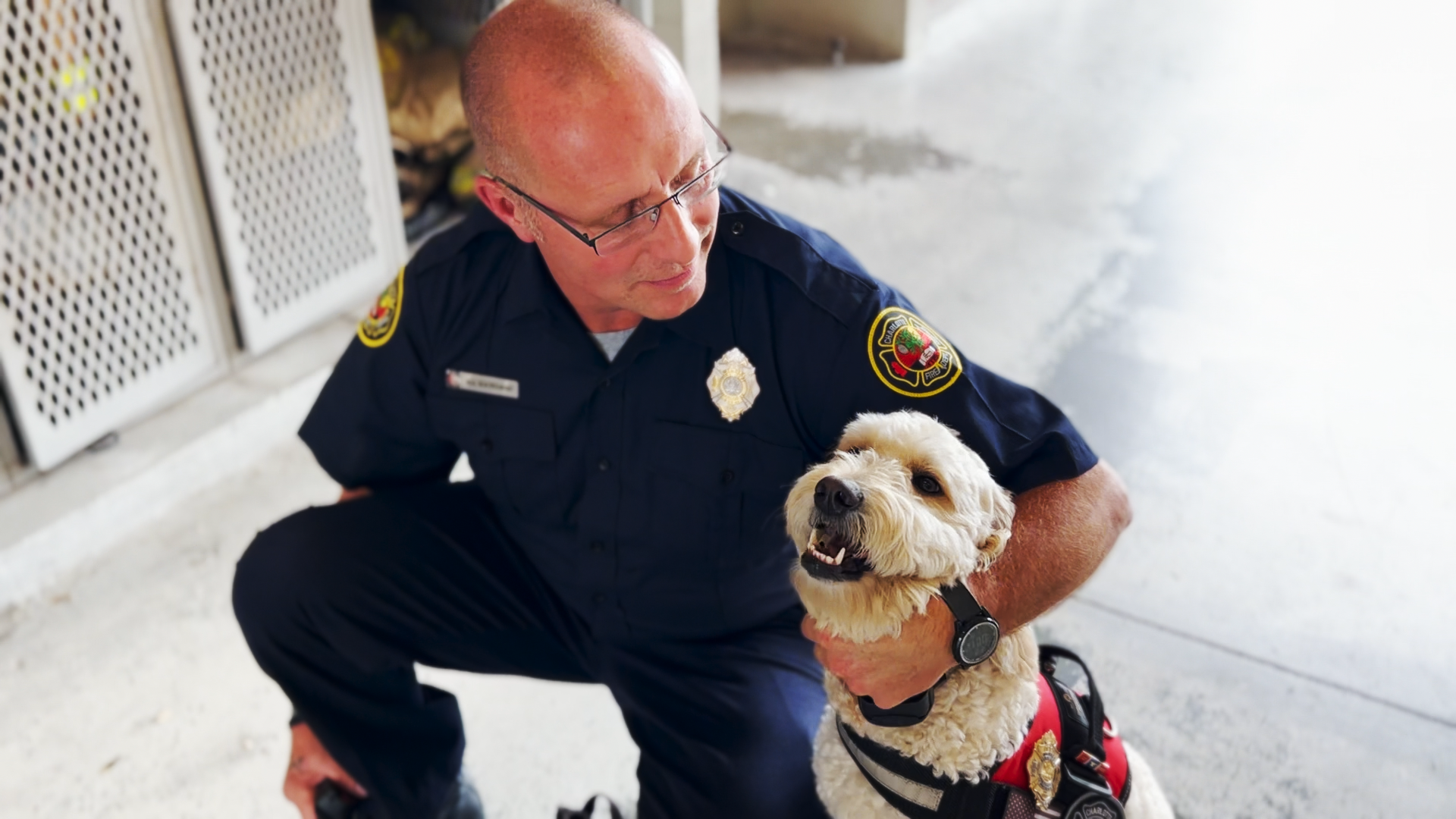 Wiatrowski hugs a smiling Phoenix while he kneels next to her on the floor of Firehouse 27.