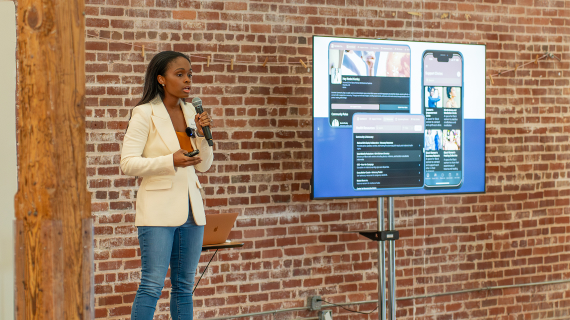 Neshé Conley presents on stage at a gALPHA program event.