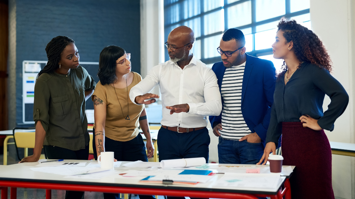 A diverse group of individuals gather around a table to work together.