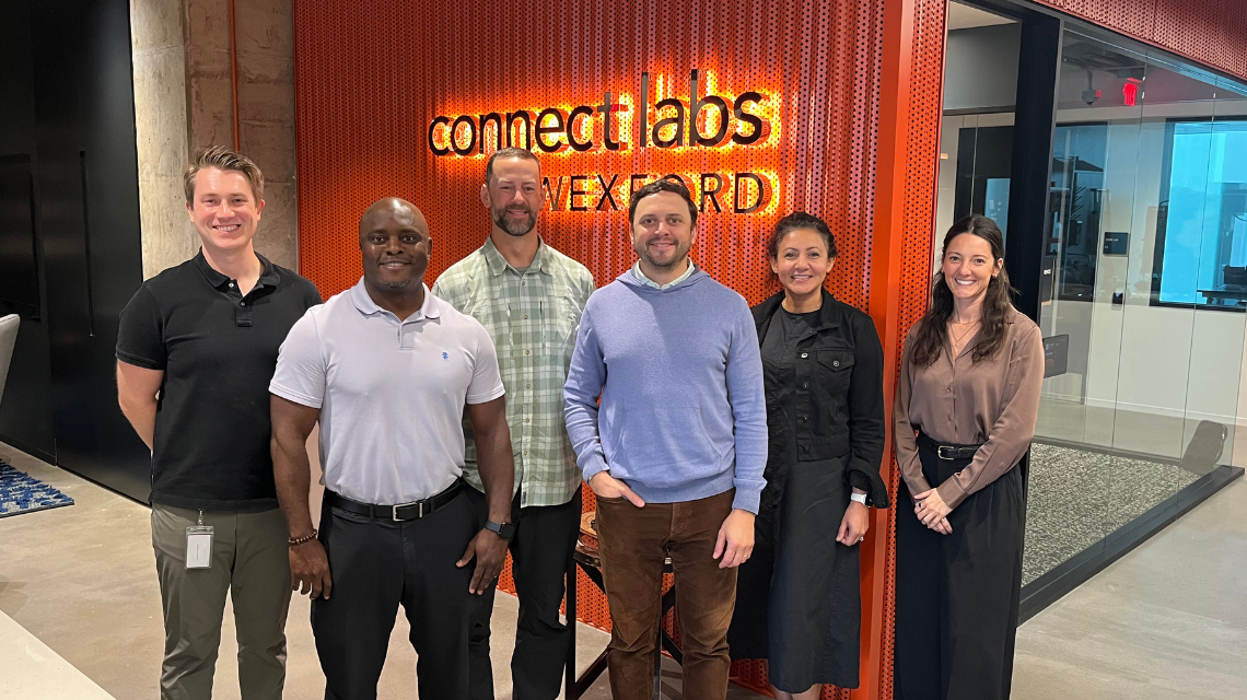 Members of the new fall gBETA cohort pose together for a photo in front of an orange background.