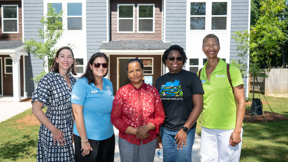 City and Habitat for Humanity staff pose with the new homeowner outside of her duplex.