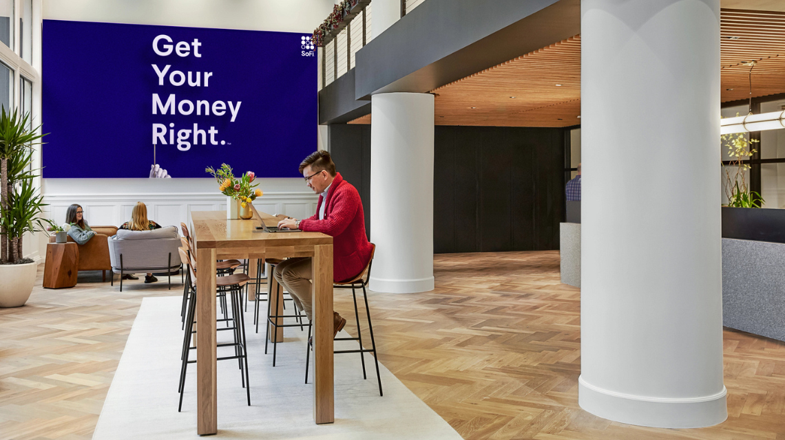 Interior of Charlotte SoFi office. A man sits at a high rise table.