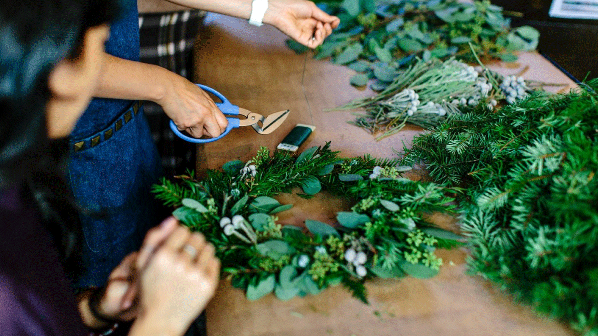 Person holding scissors creating wreaths