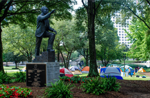 MLK statue with DNC protestor tents in park behind statue
