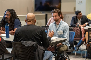 Man sitting at table smiling while talking to others