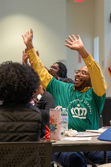 Man waving hands in the air while wearing a Civic Leadership Academy shirt
