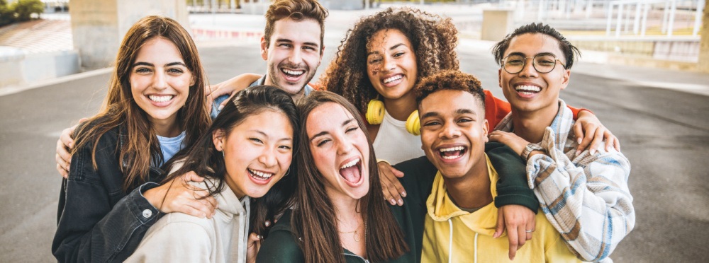 Group of kids smiling and hugged up, looking at camera.