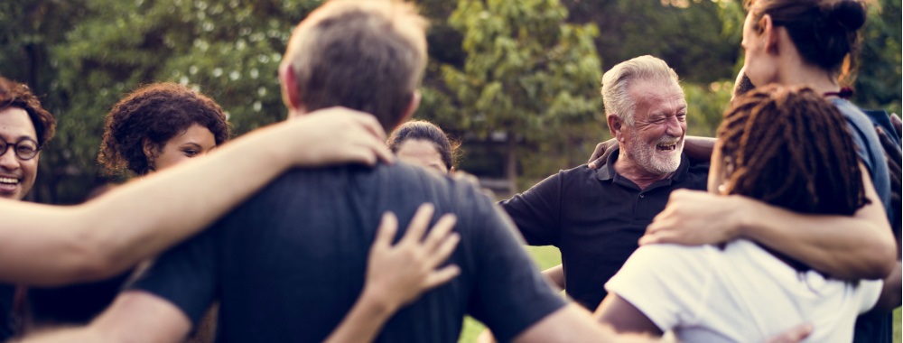 Community members in a circle with their arms around each other.