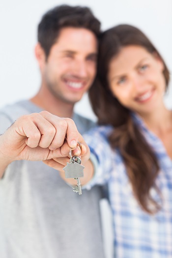 Couple holding keys to new house and smiling