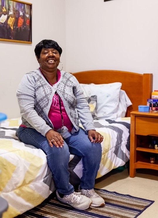 Woman sitting on bed smiling.