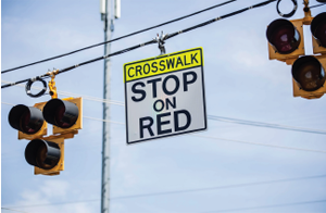 Traffic light sign: 'CROSSWALK STOP ON RED'