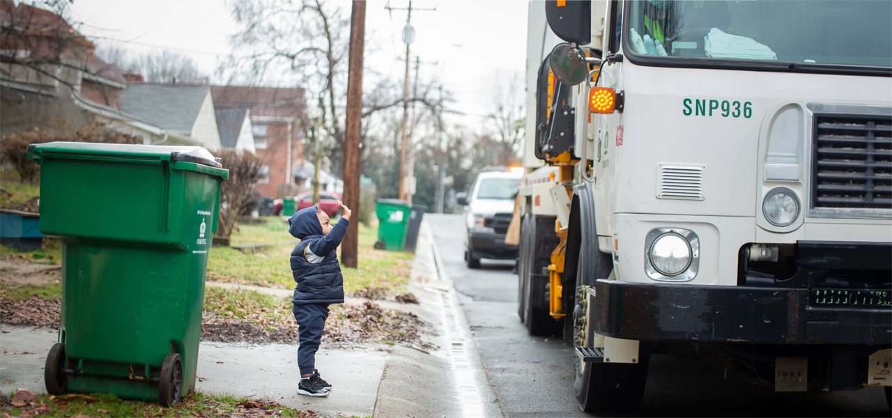 child waving at recycling collection truck