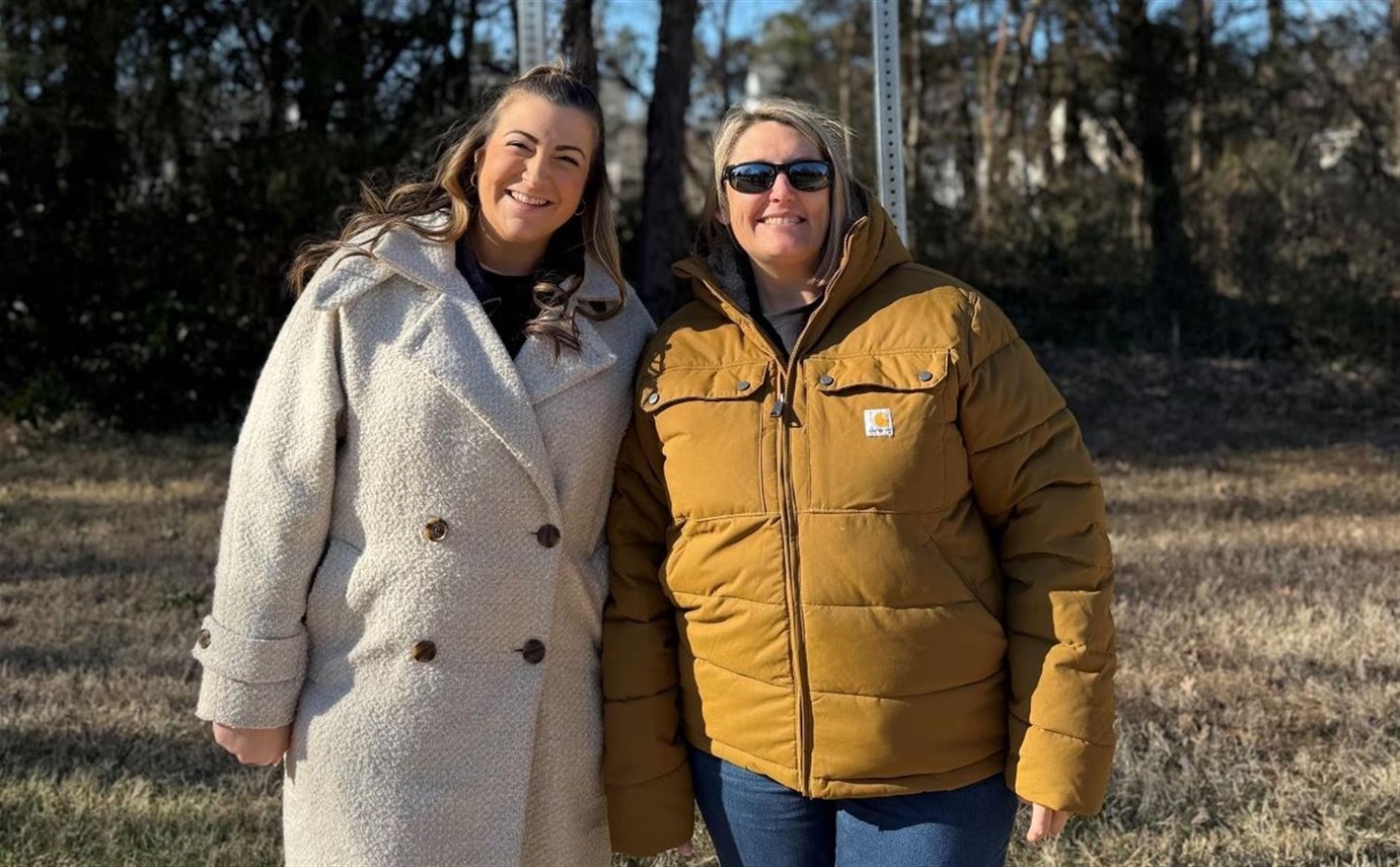 Two women standing in front of a sign